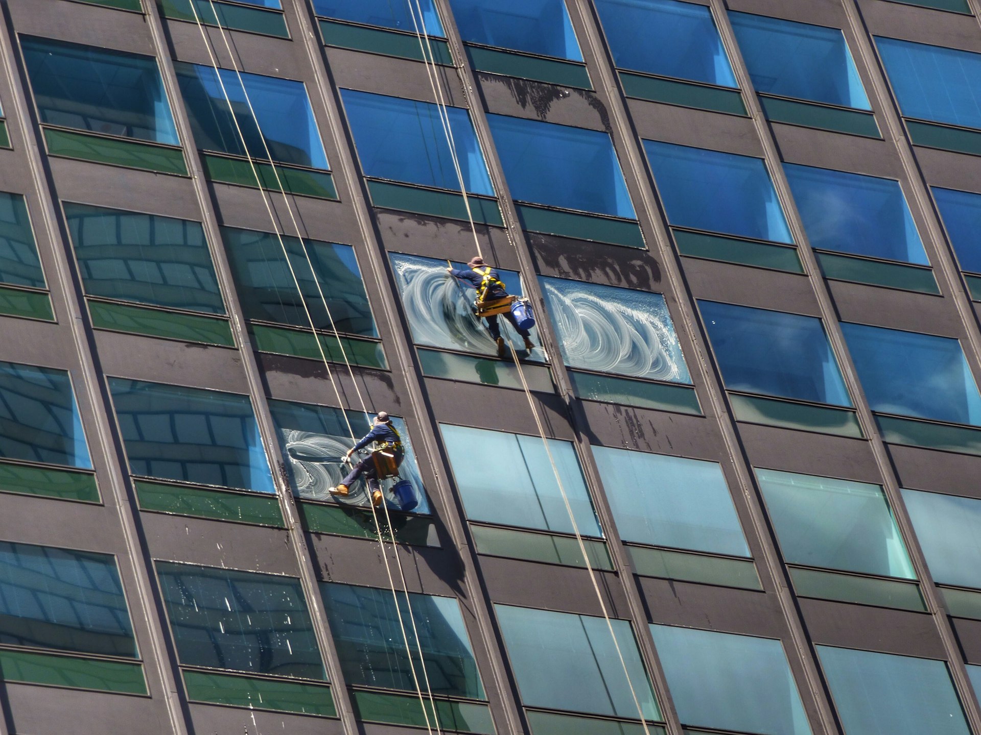 Laveurs de vitres Mavitre Clean en cordée nettoyant la façade vitrée d'un immeuble à Paris et en Île-de-France